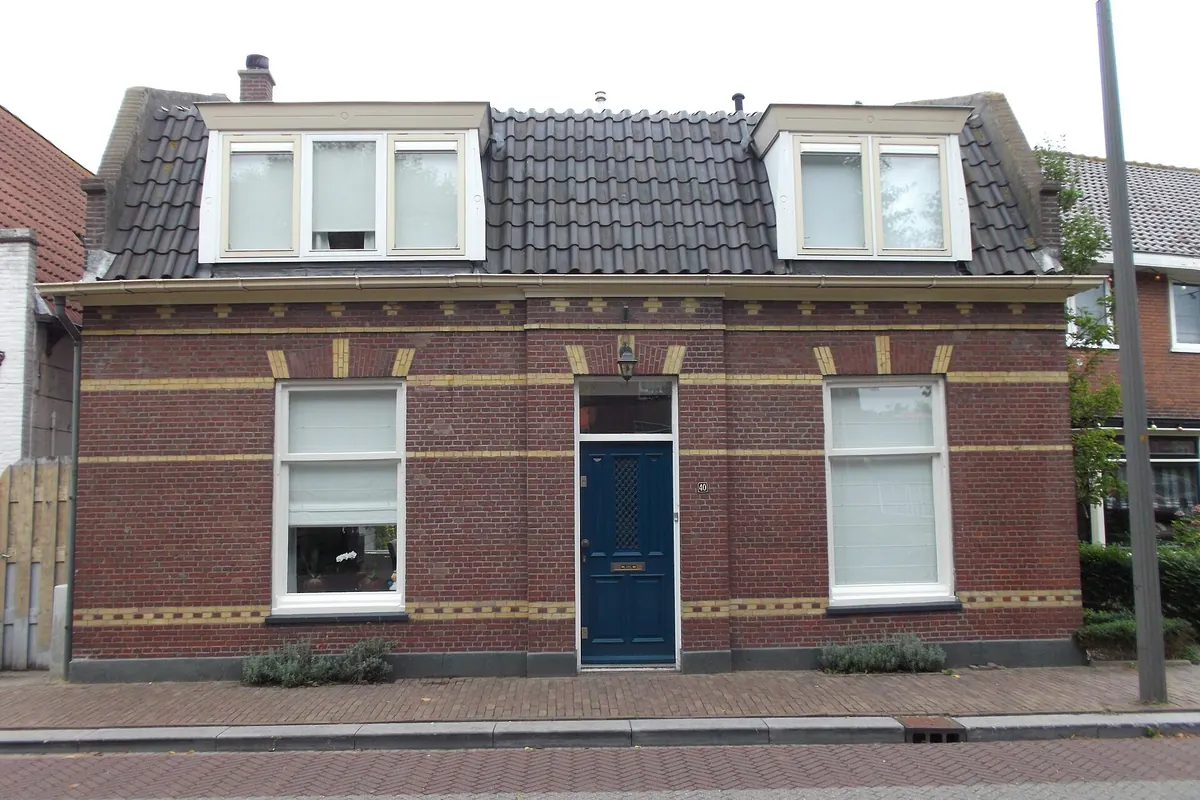 Bakstenen woning met twee witte dakkapellen in een donker pannendak aan de straatkant, voorbeeld van een dakkapel in Amsterdam