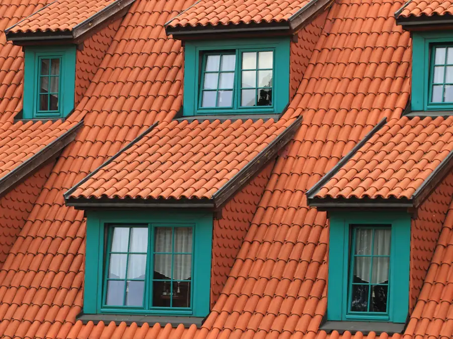 Oranje pannendak met meerdere dakkapellen met groene kozijnen, ter illustratie van een dakkapel plaatsen in Amsterdam