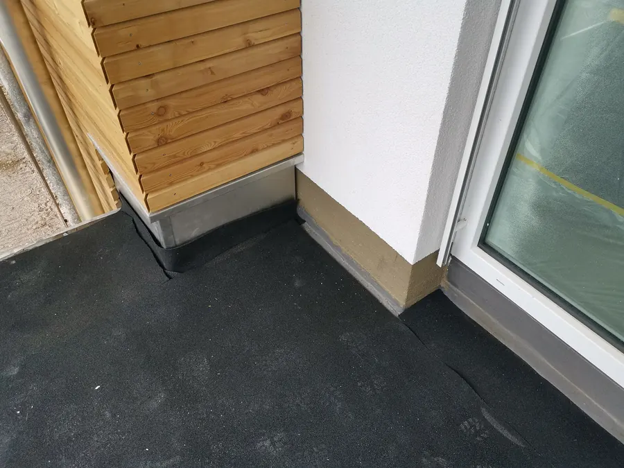 Zwarte EPDM-dakbedekking die bij een deurkozijn omhoog is gezet, ter illustratie van een plat dak in Amsterdam